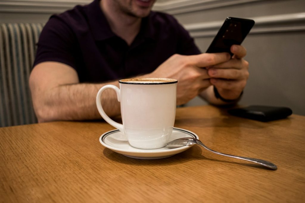 Person using a smartphone at a cafe, illustrating mobile browser and Android app access