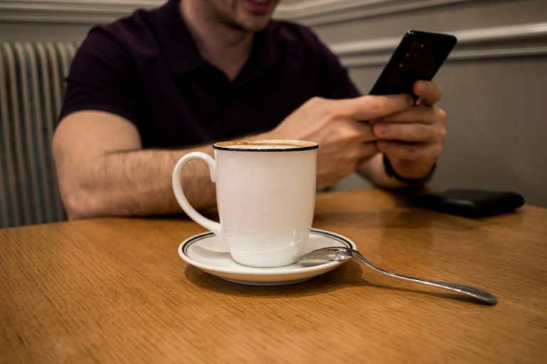 Person using a smartphone at a cafe, illustrating mobile browser and Android app access